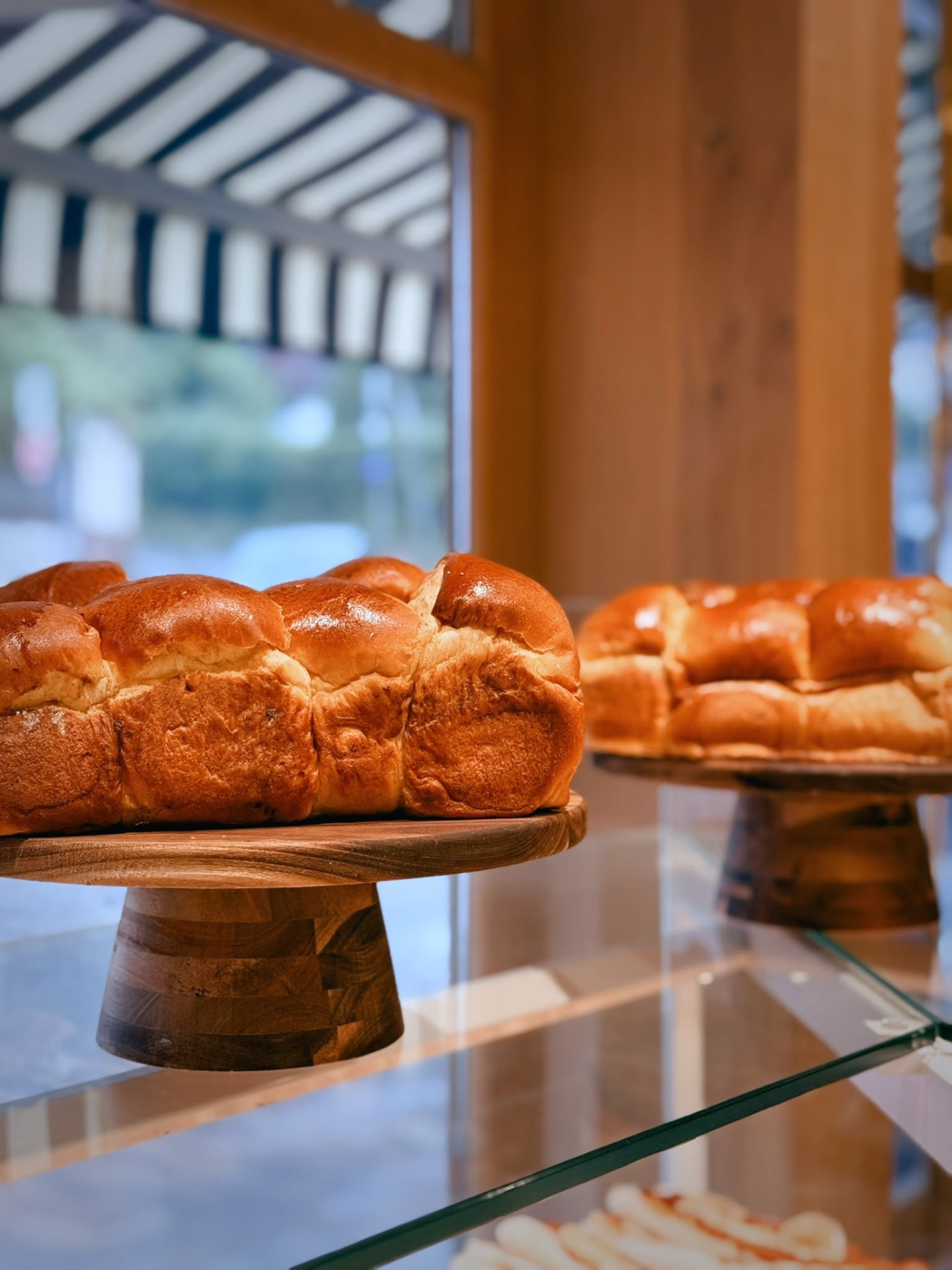 Brioches dorées sur présentoirs en bois devant la vitrine